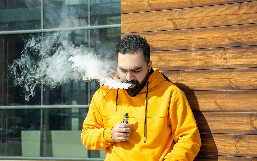 A man is coughing while vaping